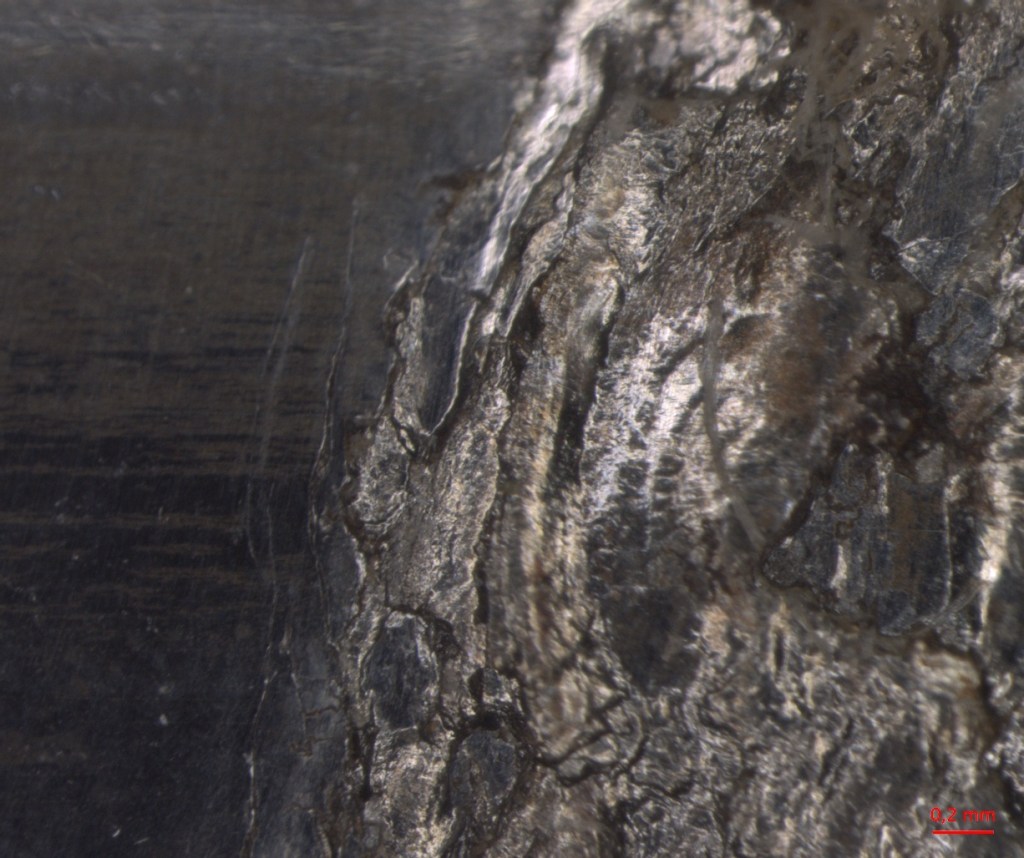 Close-up view of a metallic surface showing intricate textures and reflections.